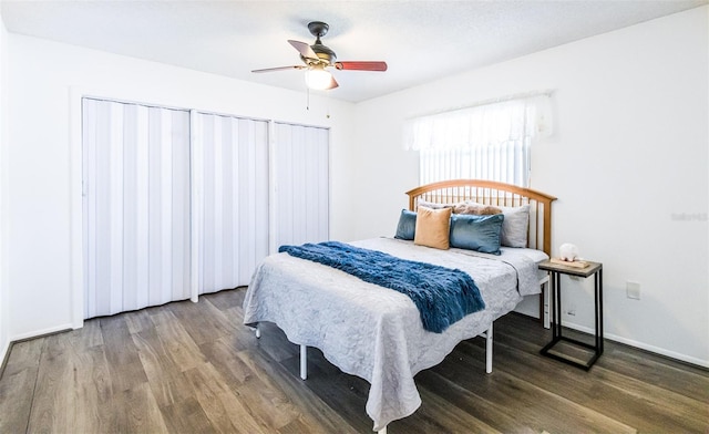 bedroom featuring ceiling fan, wood finished floors, two closets, and baseboards