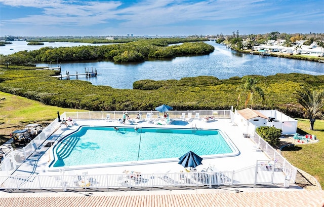 pool with a patio area, a water view, and fence