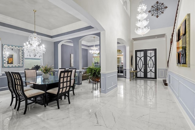 dining area with arched walkways, a chandelier, a decorative wall, and a tray ceiling