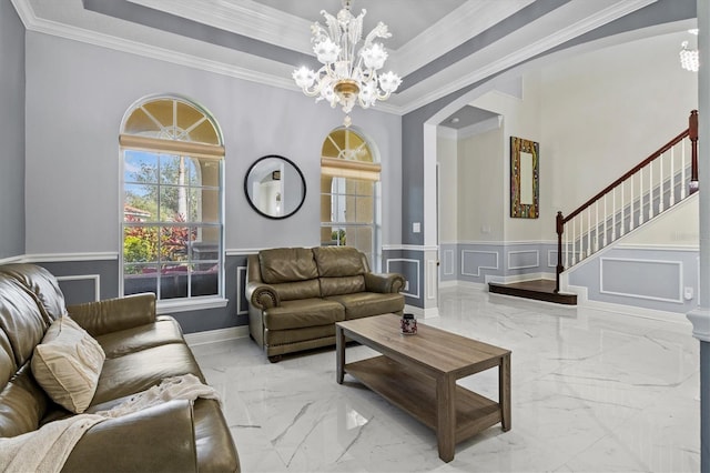 living room with marble finish floor, a raised ceiling, a decorative wall, and wainscoting