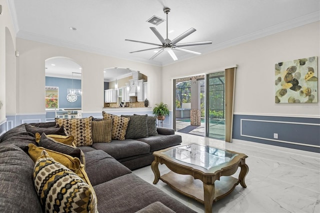 living room with ceiling fan, a wainscoted wall, visible vents, marble finish floor, and ornamental molding