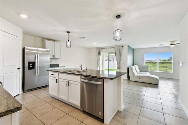 4918 Gray Owl Ter, Palmetto, FL 34221 - kitchen with stainless steel appliances, light tile patterned floors, white cabinets, a center island with sink, and pendant lighting