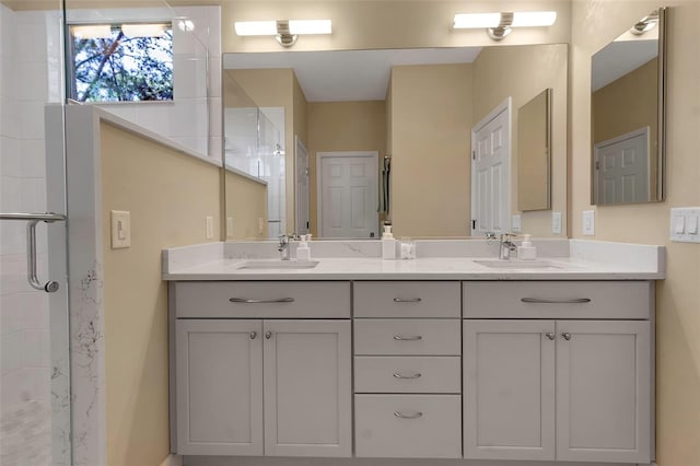 full bath with tiled shower, a sink, and double vanity