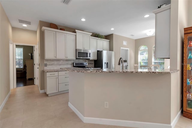 kitchen with tasteful backsplash, visible vents, appliances with stainless steel finishes, light stone countertops, and recessed lighting