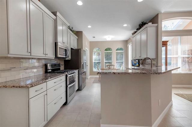 kitchen with light tile patterned floors, light stone countertops, stainless steel appliances, backsplash, and recessed lighting