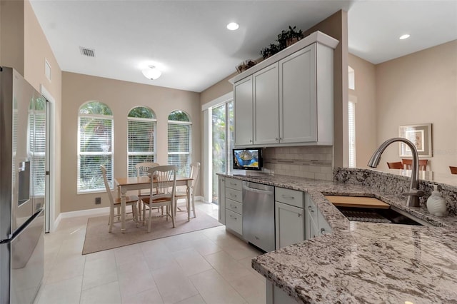 kitchen featuring light stone countertops, visible vents, appliances with stainless steel finishes, and a sink