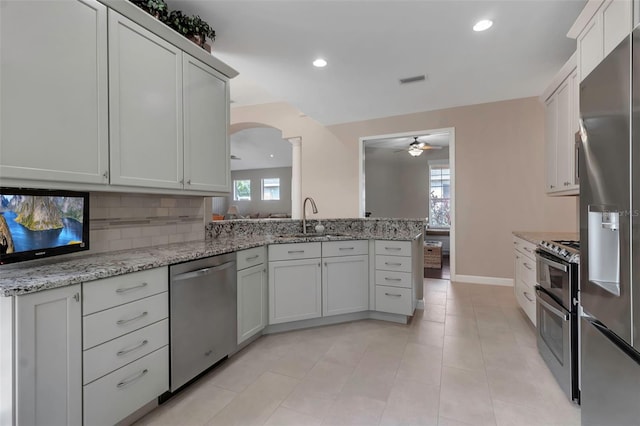 kitchen with light stone counters, recessed lighting, a sink, appliances with stainless steel finishes, and tasteful backsplash