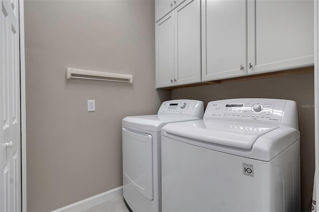 laundry room featuring separate washer and dryer, cabinet space, and baseboards