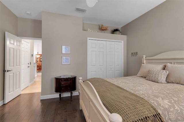 bedroom with baseboards, a closet, visible vents, and dark wood-style flooring