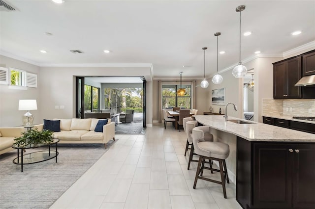 kitchen featuring backsplash, visible vents, open floor plan, and a sink