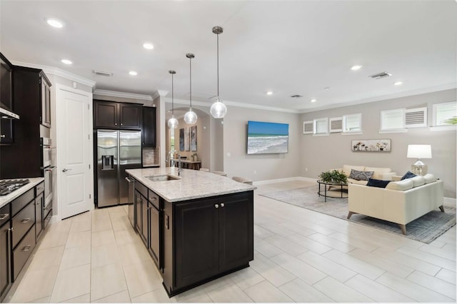 kitchen featuring visible vents, open floor plan, stainless steel built in fridge, gas stovetop, and a sink