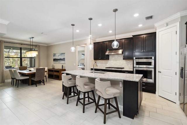 kitchen featuring tasteful backsplash, visible vents, appliances with stainless steel finishes, a sink, and under cabinet range hood