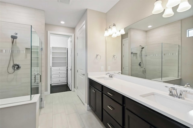 bathroom featuring a spacious closet, a sink, a shower stall, and double vanity