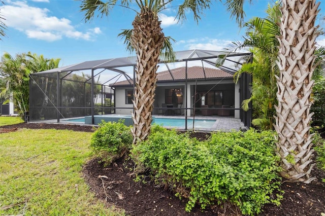 back of house with a lanai, a tile roof, an outdoor pool, and a yard