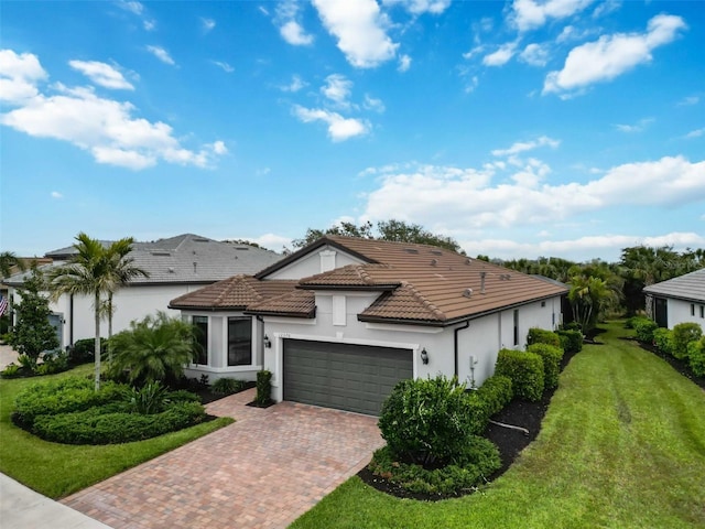 view of front of house with a garage, a tiled roof, decorative driveway, stucco siding, and a front yard