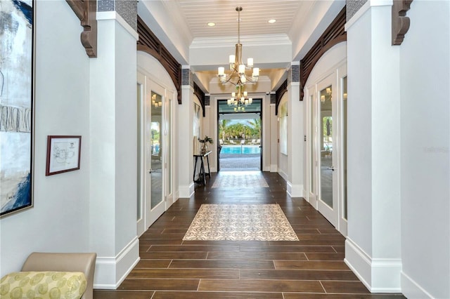 entryway with a notable chandelier, wood finish floors, baseboards, french doors, and ornamental molding