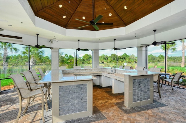 sunroom / solarium featuring a tray ceiling, a sink, and wood ceiling