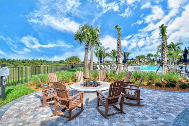 view of patio / terrace featuring fence, a fire pit, and a community pool