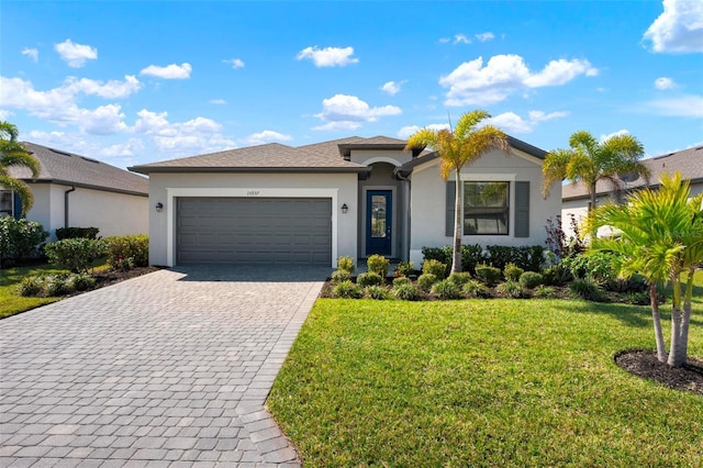 ranch-style home featuring decorative driveway, a front yard, an attached garage, and stucco siding