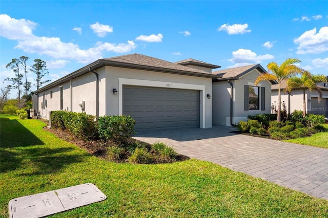 ranch-style home featuring stucco siding, a front lawn, decorative driveway, and a garage