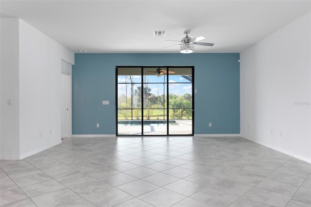 spare room with light tile patterned flooring, a ceiling fan, visible vents, and baseboards