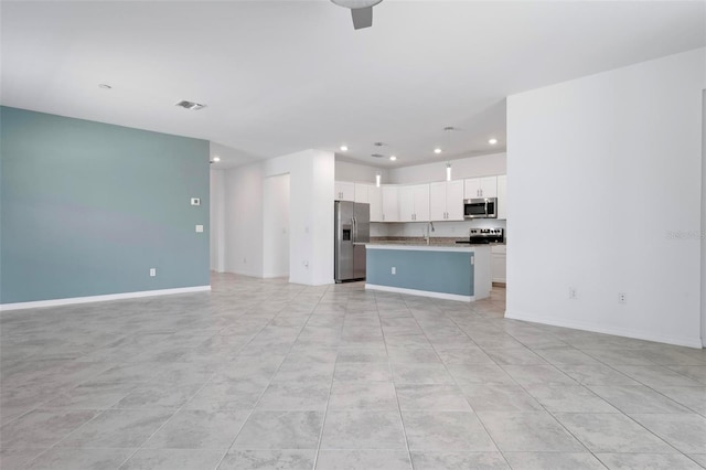 unfurnished living room featuring visible vents, recessed lighting, baseboards, and a sink