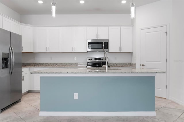 kitchen featuring a sink, pendant lighting, white cabinets, stainless steel appliances, and a kitchen island with sink