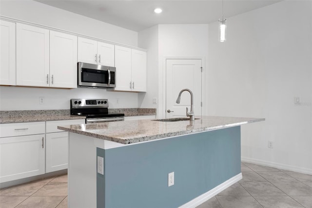 kitchen featuring light stone countertops, an island with sink, a sink, appliances with stainless steel finishes, and white cabinetry