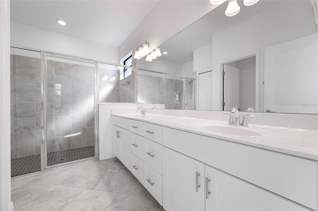 bathroom with double vanity, a shower stall, and a sink