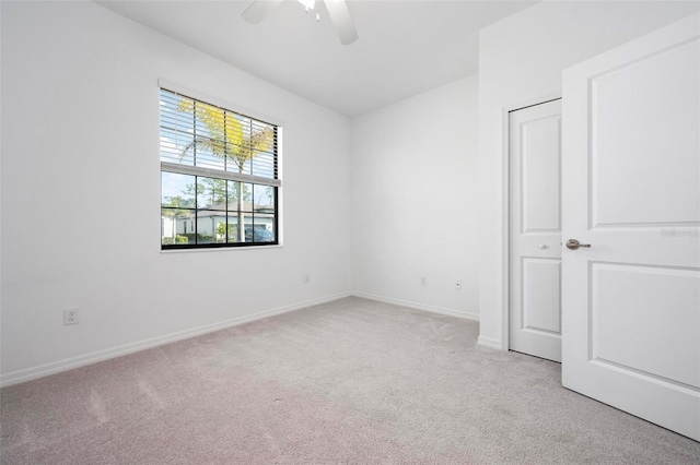 unfurnished bedroom featuring light colored carpet, a ceiling fan, and baseboards