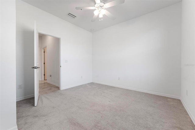 unfurnished room featuring baseboards, light colored carpet, visible vents, and ceiling fan