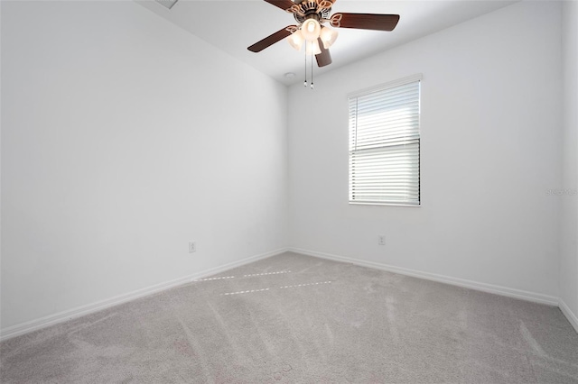 carpeted spare room with a ceiling fan and baseboards