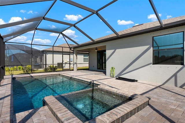 view of swimming pool featuring ceiling fan, a pool with connected hot tub, glass enclosure, and a patio