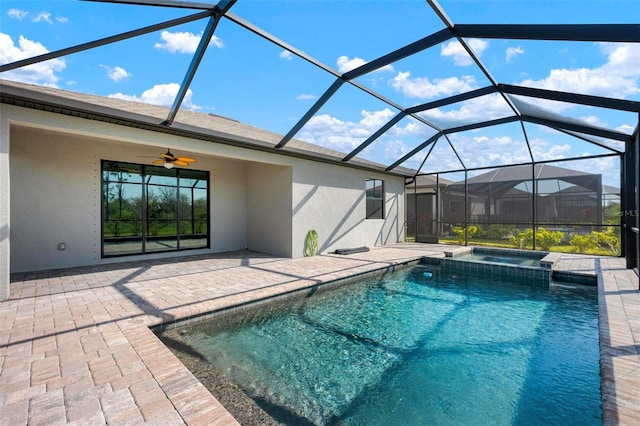 view of swimming pool with glass enclosure, a patio, a ceiling fan, and a pool with connected hot tub