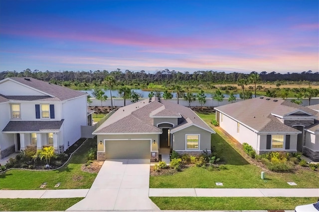 traditional-style house with a water view, driveway, a front lawn, and an attached garage