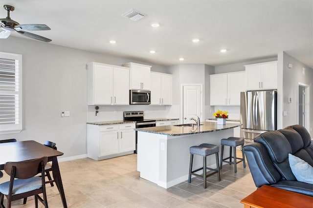 kitchen with stainless steel appliances, a breakfast bar, visible vents, open floor plan, and backsplash