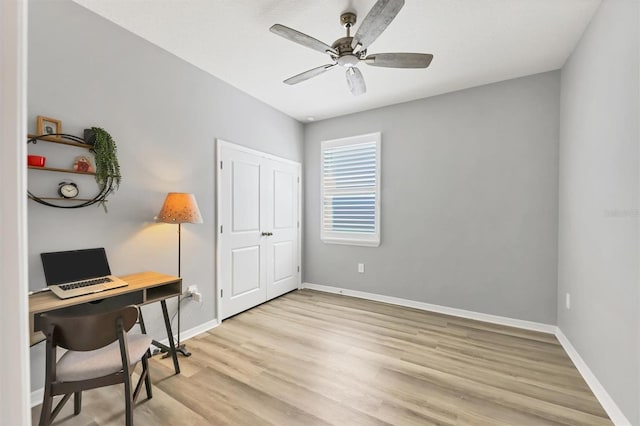 office space with light wood-style floors, ceiling fan, and baseboards