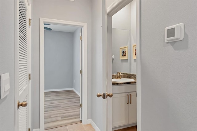 hallway featuring baseboards and a sink