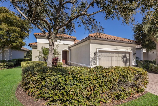 mediterranean / spanish-style house with a garage, a front lawn, stucco siding, and a tile roof