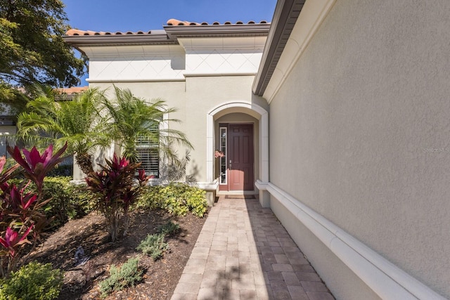 view of exterior entry featuring a tile roof and stucco siding