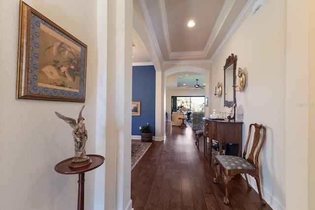 corridor with dark wood-style floors, baseboards, recessed lighting, arched walkways, and ornamental molding