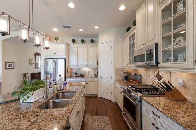 kitchen with visible vents, dark wood finished floors, a sink, high quality appliances, and backsplash