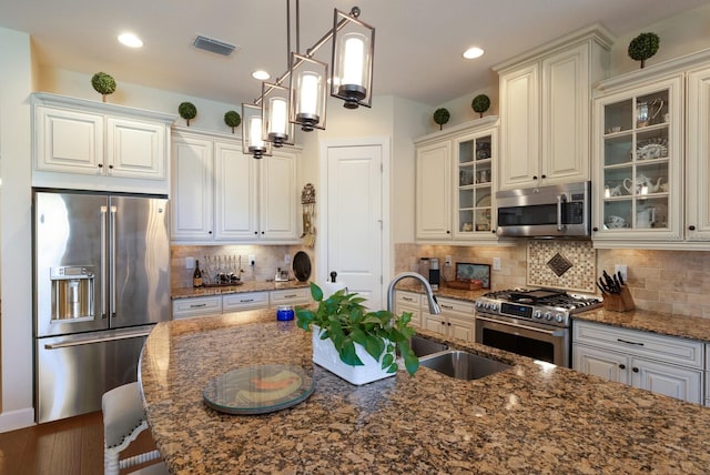 kitchen featuring tasteful backsplash, visible vents, appliances with stainless steel finishes, and glass insert cabinets