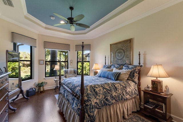 bedroom with a raised ceiling, dark wood-style floors, visible vents, and ornamental molding