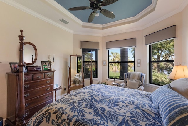 bedroom featuring a ceiling fan, baseboards, visible vents, a tray ceiling, and ornamental molding