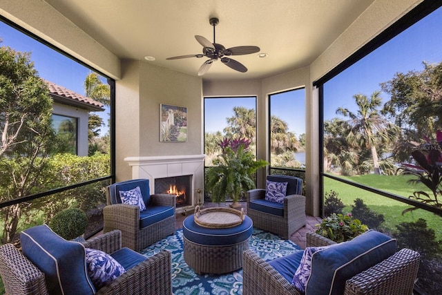 sunroom with a wealth of natural light, a lit fireplace, and ceiling fan