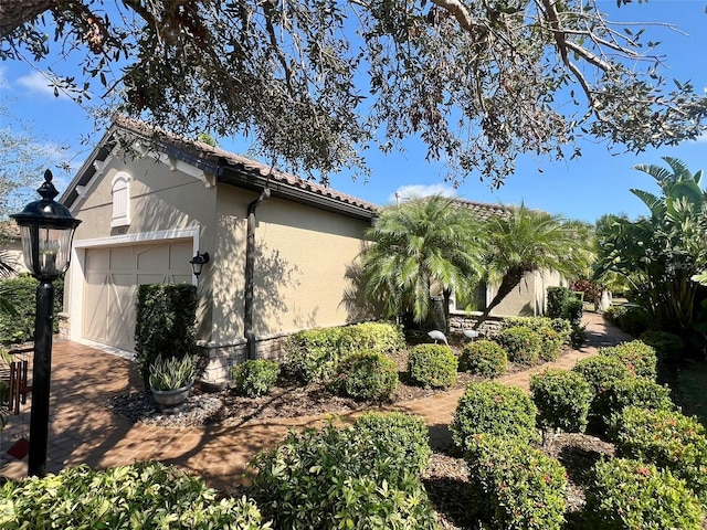 5031 Serata Dr, Bradenton, FL 34211 - view of side of property with an attached garage, a tile roof, and stucco siding