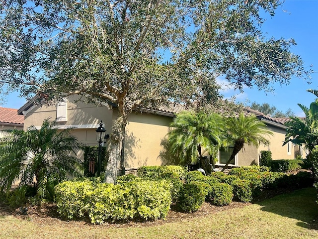 view of side of property with a tile roof and stucco siding