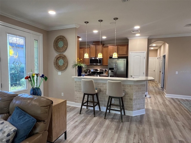 5031 Serata Dr, Bradenton, FL 34211 - kitchen featuring appliances with stainless steel finishes, arched walkways, crown molding, and a kitchen bar