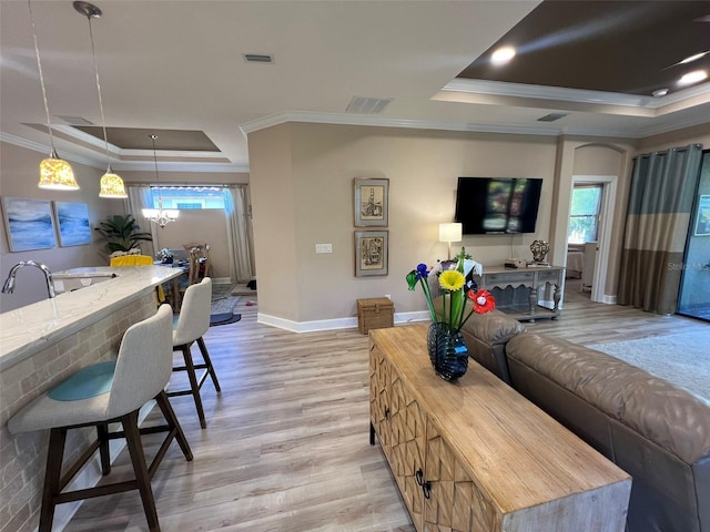 5031 Serata Dr, Bradenton, FL 34211 - living room featuring baseboards, visible vents, a tray ceiling, crown molding, and light wood-type flooring
